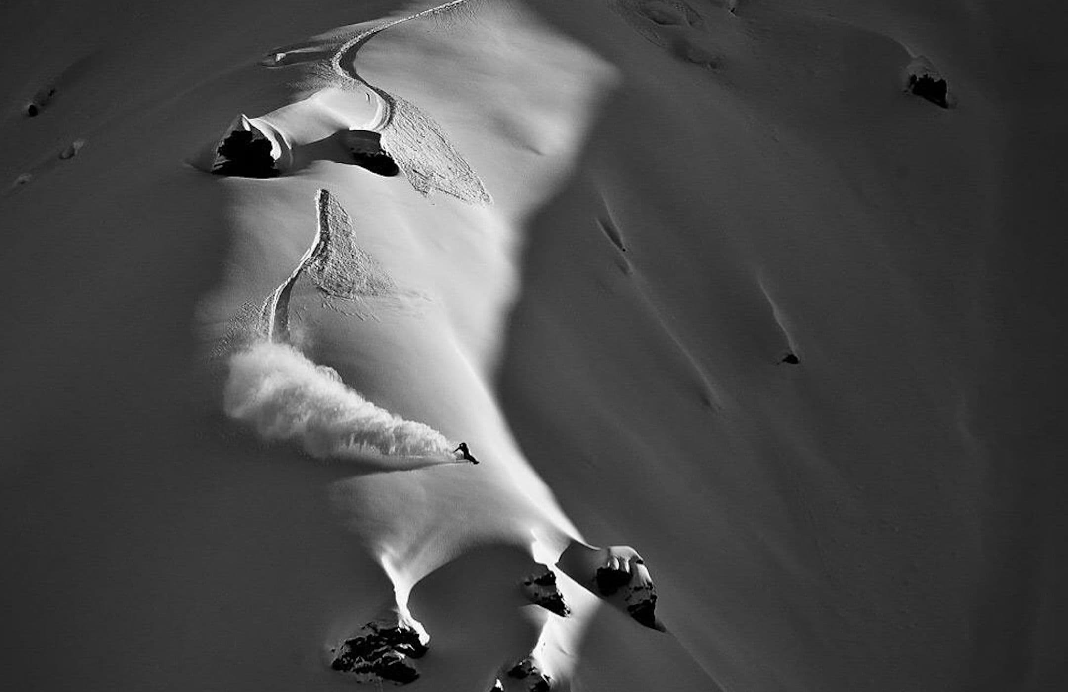 Emilien Badoux en snowboard dans une pente de poudreuse, en noir et blanc